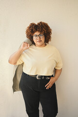 Beautiful happy smiling curvy plus size African black woman afro hair posing in beige t-shirt, jeans, stylish glasses on beige background. Body imperfection, acceptance body positive diversity concept