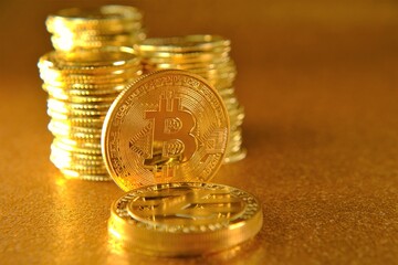 Virtual currency. Money and finance. Gold bitcoin on a golden blurred background. Blockchain cryptocurrency.cryptocurrency investing concept.bitcoin coin and columns of gold coins on golden background