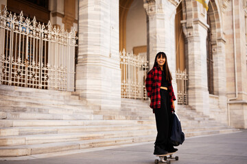 Portrait of young beautiful girl with skateboard. Happy smiling woman relaxing outdoors..