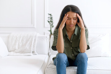 Stressed young indian woman touching head and feels dizzy, suffering from headache and migraine...