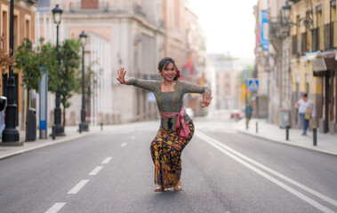young happy and beautiful Asian woman wearing traditional Balinese kebaya dress - Indonesian girl doing Bali dance on street during holidays travel in Europe
