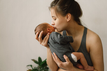 Mother holds and hugs her newborn baby son at home. Happy infant and mom.