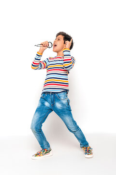 Young boy emotionally sings into an imaginary microphone against white background in studio