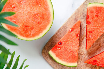 three triangular pieces of watermelon on motherboard and half an organic watermelon on a white marble table