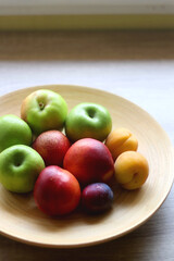 Wooden bowl with various colorful fruit on dark background. Selective focus.