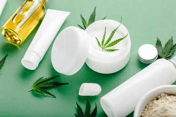 Hemp moisturizing cream in white jar with CBD oil cannabis leaf and set skin care cosmetics on...