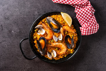 Traditional spanish seafood paella on black background. Top view