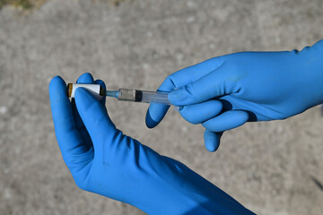 syringe with injection in a blue hand against the grey background 