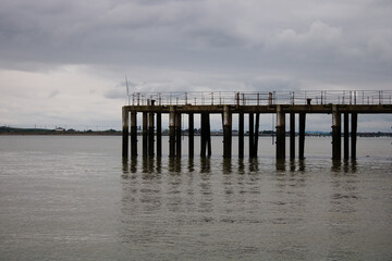 Part of old abandoned pier in the sea, Kent, England, Isle of Grain, on a cloudy day