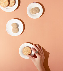Woman's hand with tasty cookies on a pastel peach background. Colorful creative breakfast idea.