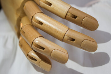 Wooden mannequin’s hand on the white fabric background