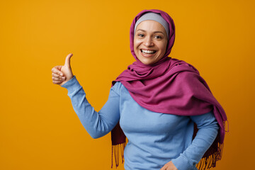 Middle eastern woman in headscarf smiling and showing thumb up