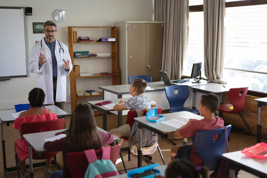 Caucasian male doctor talking to group of diverse students sitting in the class at school