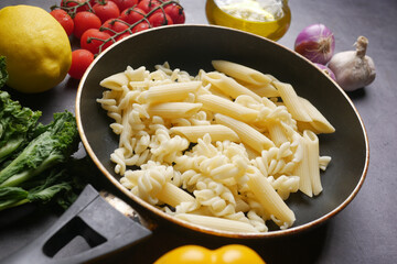 fusilli in a pan on black background.
