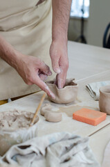 A pottery master makes a jug from clay. Hands close up