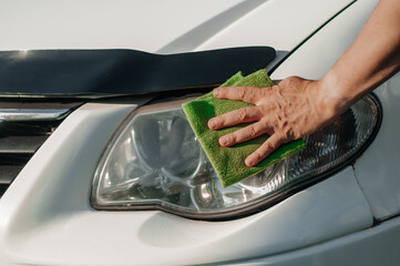 Man cleaning car with microfiber cloth, car detailing (or valet) concept. Selective focus.