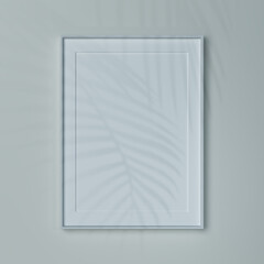 Empty vertical frame on a wall in natural light. Mockup of a picture or poster  A2 in white wooden...