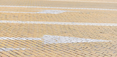 Arrow traffic signs on a cream color paved road