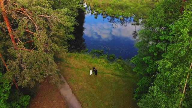 Aerial ascending view male photographer shoot wedding couple. Wedding photography shoot in nature in scenic Lithuania countryside