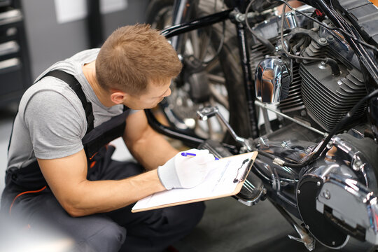 Foreman in service repair center diagnoses parts on motorcycle