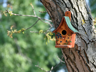 A bird house on a tree, decorated with a drawing of flowers