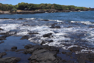 Beautiful view of the ocean waves hitting the black volcanic rocky beach in Kailua-Kona - obrazy, fototapety, plakaty
