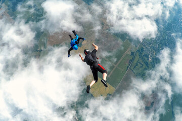 Two skydivers over the clouds during freefall - obrazy, fototapety, plakaty