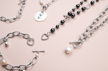 Fototapeta premium Top view of stylish jewelry on a pastel pink background surface. Woman trendy fashion accessories arrangement.
