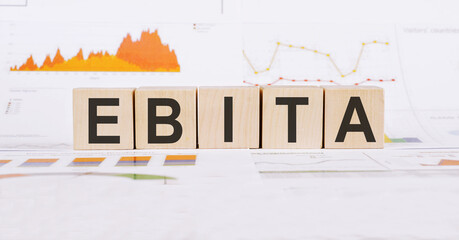 On a light background, graphs, diagrams and wooden cubes with the word EBITA - reduced profit before interest, taxes, depreciation and amortization.