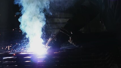 Welding work at the factory. A worker with a welding machine performs welding work on metal.
