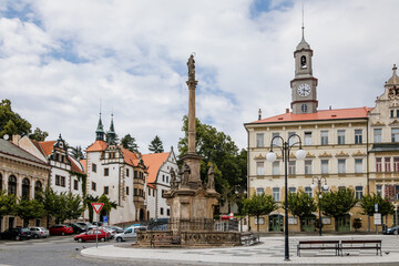 Fototapeta na wymiar Benesov nad Ploucnici, North Bohemia, Czech Republic, 26 June 2021: Marian Column with baroque statues at main town square, old saxoxy renaissance Morzinov Castle and Town Hall at summer sunny day