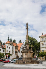 Obraz premium Benesov nad Ploucnici, North Bohemia, Czech Republic, 26 June 2021: Marian Column with baroque statues at main town square, old saxoxy renaissance Morzinov Castle and Town Hall at summer sunny day