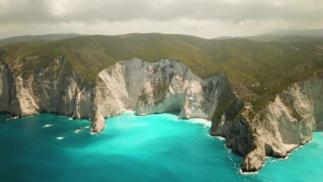 4K Aerial footage of stunning white rocks and turquoise clean water near to Navagio beach known as Shipwreck Beach or Shipwreck Cove located in Zakynthos island, Greece. Dramatic weather.