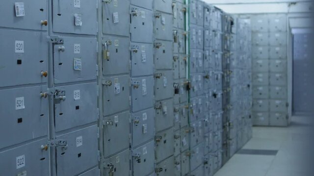 Camera moves along Safe Deposit Boxes in a bank vault room . Security room with many locked cases and numbers  on it . Safe metal Cases with padlock for saving money , jewelry and documents
