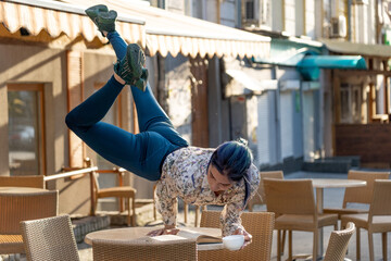 Woman drink coffee and read a book in cafe outdoor. Concept of individuality, creativity and originality