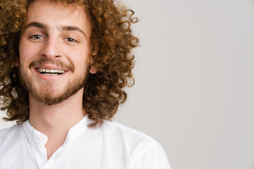 Young curly man with ginger hair smiling and looking at camera