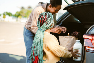 Black woman and her daughter getting out food from car trunk