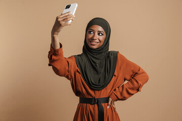 Young muslim woman in hijab taking selfie photo on mobile phone