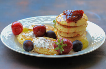 Delicious pancakes with berries, honey or grape syrup. Homemade pancakes and sweet syrup on a white plate isolated.
