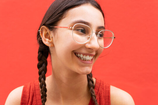 Happy woman with pigtails on red background in city