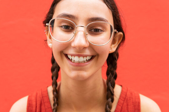Happy woman with pigtails on red background in city