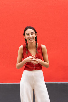 Happy woman with pigtails on red background in city
