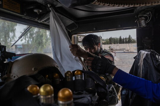 A member of Afghan Special Forces confiscates a Taliban flag mounted on a tree during the rescue mission of a police officer besieged at a check post surrounded by Taliban, in Kandahar province