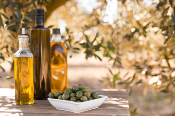 green olives and oil on table in olive grove