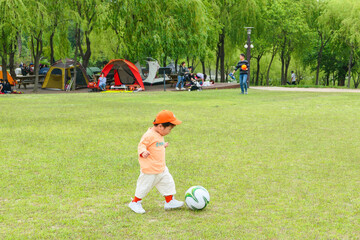 푸른 잔디밭 위에서 축구공을 갖고 노는 남자아이