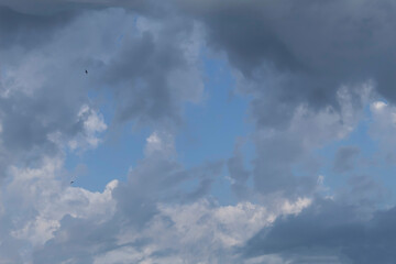 In the blue sky, gray rain clouds are crawling over the white clouds.