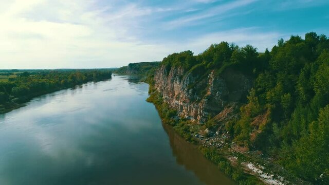 Evening in the wild. The dense forest grows on an impregnable rock. The blue sky is reflected on the surface of the water in the river. A place for solitude and relaxation. High quality. 4k footage.