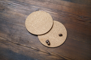 Blank cork beer coasters and coffee beans on wooden background. Responsive design template.