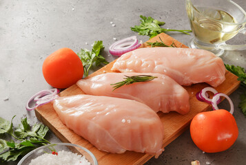 chicken fillet with herbs, tomatoes, onions and olive oil on a cutting board