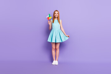 Full body photo of attractive nice young woman hold hand pinwheel smile isolated on purple color background